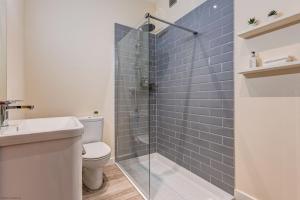 a bathroom with a toilet and a shower with blue tiles at Romney Barn in Minster Lovell