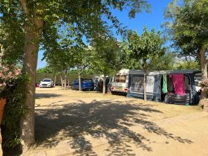 een groep voertuigen geparkeerd in een veld met bomen bij Camping Del Mar in Malgrat de Mar