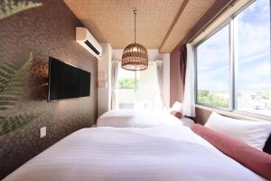 Duas camas num quarto com uma televisão e uma janela em Nankishirahama Hotel Akariya em Shirahama