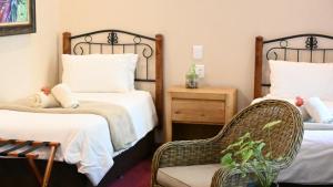 a hotel room with two beds and a chair at LUXURY FAMILY EN-SUITE ROOM @ 4 STAR GUEST HOUSE in Middelburg