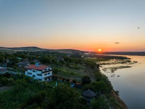 a sunset over a river with a house on a hill at Laguna Nuferilor Habitat in Somova