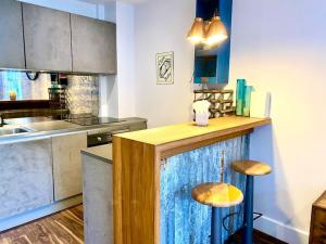 una cucina con bancone e 2 sgabelli di Stunning Little House on Poole Quay - Free Secure Parking & WiFi - in the heart of the Old Town - Great Location - Free Parking - Fast WiFi - Smart TV - Newly decorated - sleeps 2! Close to Poole & Bournemouth & Sandbanks a Poole