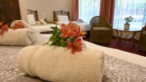 una camera d'albergo con due letti con asciugamani e fiori di LUXURY FAMILY EN-SUITE ROOM @ 4 STAR GUEST HOUSE a Middelburg