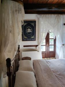 - une chambre avec 2 lits avec des rideaux blancs et une fenêtre dans l'établissement Feggaropetra Inn Magic Mountain House, à Palaios Panteleimonas