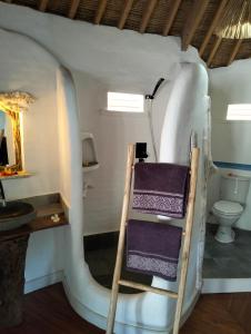 a bathroom with a toilet and a shelf with towels at SHAYA cottage in Sekotong