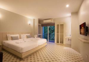 a bedroom with a large white bed and a bathroom at Nature Pine Phuket เนเชอร์ไพน์ภูเก็ต in Rawai Beach