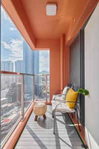 Sienna Ambassador Residence في بوسان: غرفة برتقالية مع كرسي ونوافذ كبيرة