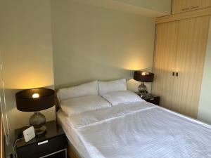 - une chambre avec un lit blanc et 2 lampes dans l'établissement Supreme Condo at Brenthill Baguio, à Baguio