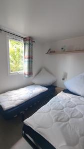 2 camas en una habitación con ventana en MOBILHEIM HERZ LAUWERSOOG - Chalet Robbengat, en Lauwersoog
