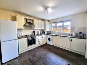 a kitchen with white cabinets and a white refrigerator at Detached House with Free Parking Long Stay Discounts in Thurcaston