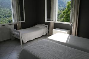 two beds in a room with two windows at Le Refuge Orezza in Piedicroce
