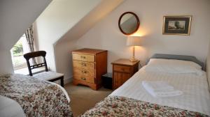 a bedroom with a bed and a dresser and a mirror at Glen Cottage in Comrie