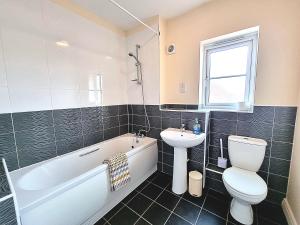 La salle de bains est pourvue d'un lavabo, de toilettes et d'une baignoire. dans l'établissement Detached House with Free Parking Long Stay Discounts, à Thurcaston
