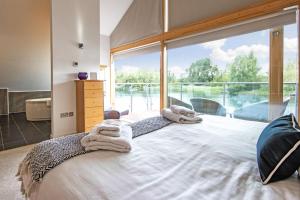 a bedroom with a large window with towels on a bed at Waters Edge 04, Waterside Lodge P in South Cerney