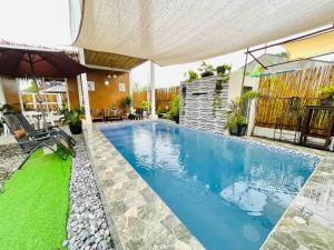 a swimming pool in a backyard with an umbrella at Kaha Briones Family Guest House in Tarlac