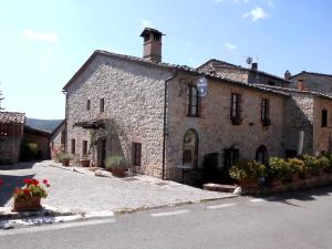 un viejo edificio de piedra con flores delante en B&B Borgolecchi , Lecchi in Chianti, en San Sano