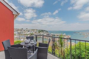 a balcony with a table and chairs and the ocean at Driftwood - New Listing in Brixham