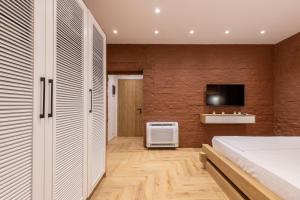 - une chambre avec un lit et une télévision sur un mur en briques dans l'établissement Vatër Apartments, à Tirana