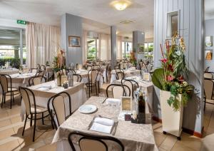restauracja z białymi stołami, krzesłami i kwiatami w obiekcie Hotel Odeon w mieście Cervia