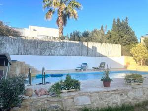 una piscina con 2 sillas y una valla en La maison les pins Chambre d'hote chez l'habitant en La Marsa