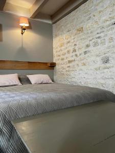 a large bed in a room with a brick wall at Le grenier d'Odette in Sainte-Gemme-la-Plaine