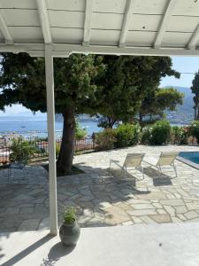 un patio con sedie, un albero e una piscina di Villa Icelle Skopelos Town Sea View Swimming Pool a Skopelos Town