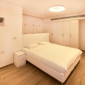 a white bedroom with a large bed and cabinets at Hapalmah one, Jerusalem, Dira 1 in Jerusalem