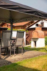 two chairs and a table under an umbrella at Ferienhaus Blick Falkenstein in Lindberg