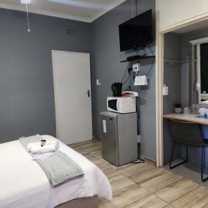 Schlafzimmer mit einem Bett, einem Schreibtisch und einem TV in der Unterkunft Rue Guesthouse in Postmasburg