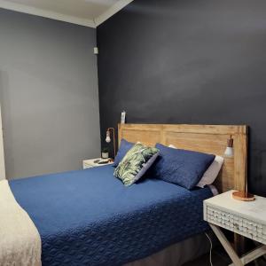 een slaapkamer met een blauw bed en een houten hoofdeinde bij Rue Guesthouse in Postmasburg