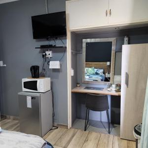 PostmasburgにあるRue Guesthouseのデスク、電子レンジが備わる小さな客室です。