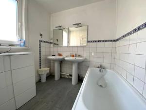 ein Badezimmer mit 2 Waschbecken, einer Badewanne und einem Spiegel in der Unterkunft VILLA ST SOPHIE in Wimereux