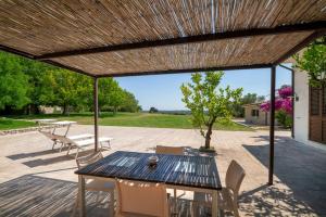 a patio with a table and chairs under a wooden roof at Podere Santa Chiara in Otranto