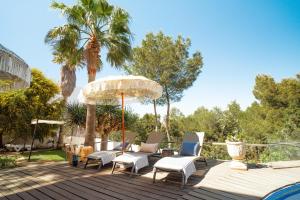 a deck with chairs and an umbrella and palm trees at Oasis Living Can Nirvana - Best Sea Sunsets in Cala Tarida