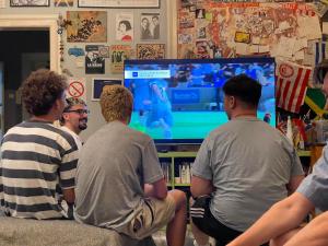 um grupo de homens sentados num sofá a jogar um jogo de vídeo em Habitat Hostel em Belgrado