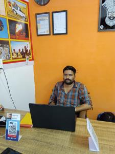 a man sitting at a table with a laptop computer at Jasmeet hotels in Jaisalmer