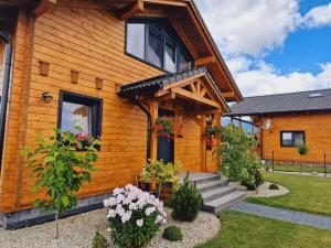 a wooden house with a porch and flowers on it at Panorama Tatry Chalets in Veľká Lomnica