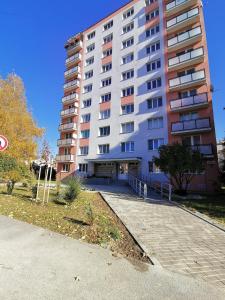 een groot wit appartementencomplex met een parkeerplaats bij Friends & Family Apartment in Trenčín