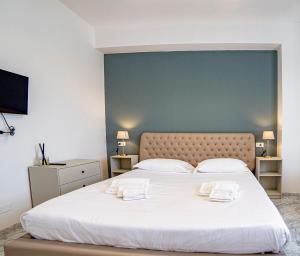 um quarto com uma grande cama branca e 2 toalhas em Meravigliosa camera con finiture di lusso appena ristrutturata em Marina di Carrara