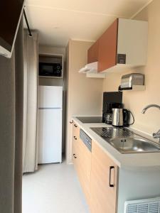 een kleine keuken met een wastafel en een koelkast bij Camping La Clape Village in Cap d'Agde