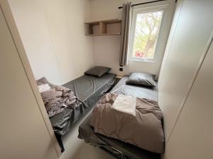 2 Betten in einem kleinen Zimmer mit Fenster in der Unterkunft Camping La Clape Village in Cap d'Agde
