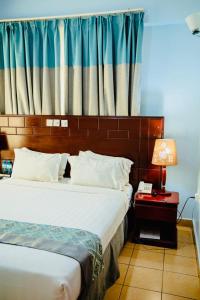 a bedroom with two beds and a night stand with a lamp at Green Mountain Hotel in Arusha