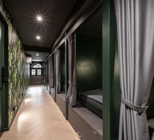 a corridor with beds in a room with green walls at Cher Hostel Bangkok in Bangkok