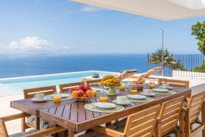 a wooden table with fruit on top of a balcony at Premium villa panoramic sea-view Calheta Pearl in Estreito da Calheta