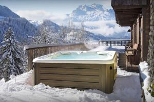 a hot tub in the snow next to a house at Chalet Morclan - OVO Network in Manigod