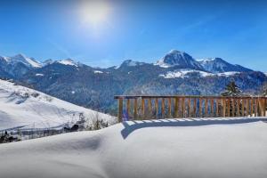 a snow covered bench with a view of mountains at Chalet Morclan - OVO Network in Manigod