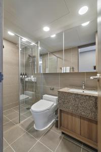uma casa de banho com um WC, um chuveiro e um lavatório. em Sienna Ambassador Residence em Busan