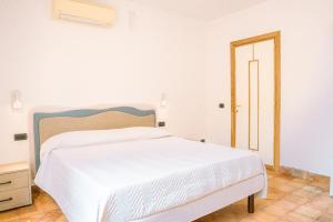 Cama blanca en habitación blanca con puerta en Residenza Ester en Amalfi