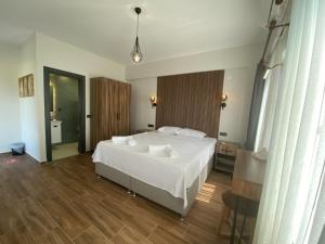 a bedroom with a large white bed and wooden floors at Tinos Otel & Bağ Evi 12 Yaş Üstü in Bozcaada