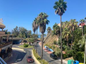 a street with palm trees and cars on the road at ArtPlatinum SUITES&APARTMENTS in Benalmádena